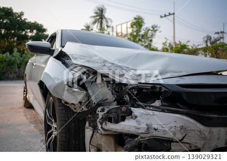 Close-up of damaged white car after front collision with visible dents and broken parts Close-up of damaged white car after front collision with visible dents and broken parts 139029321