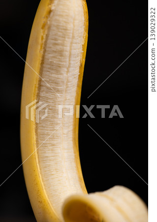 Close-up of Partially Peeled Banana on Black Background 139029322