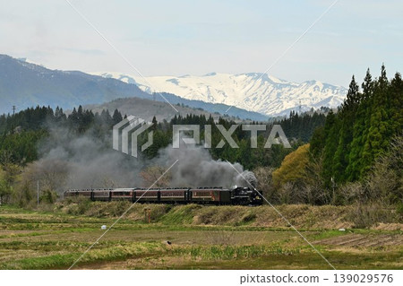 The SL Ban'etsu Monogatari train passes through Uenojiri on the Ban'etsu West Line, with the snow-capped Iideyama Mountains in the background. The SL Ban'etsu Monogatari train passes through Uenojiri on the Ban'etsu West Line, with the snow-capped Iideyama Mountains in the background. 139029576