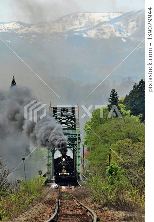 The SL Ban'etsu Monogatari train crosses the Agano River with snow-capped mountains in the background on the Ban'etsu West Line. The SL Ban'etsu Monogatari train crosses the Agano River with snow-capped mountains in the background on the Ban'etsu West Line. 139029944