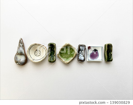 A collection of ceramic chopstick rests, arranged in a single row on a white background. A collection of ceramic chopstick rests, arranged in a single row on a white background. 139030829