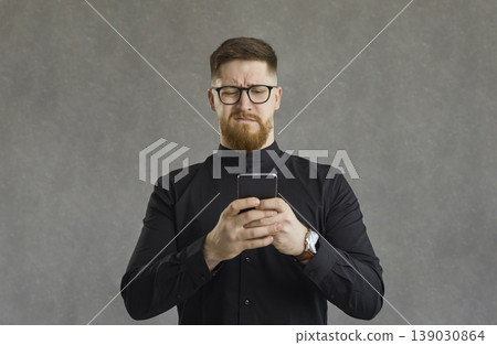 Young stylish man with phone having confused or puzzled expression studio shot 139030864