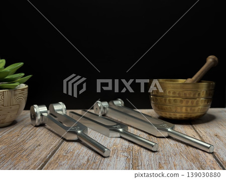 Set of Metal Tuning Forks with Singing Bowl and Succulent Plant on Wooden Table for Sound Healing Meditation Wellness Therapy Holistic Vibration Frequency Concept with Dark Background Set of Metal Tuning Forks with Singing Bowl and Succulent Plant on Wooden Table for Sound Healing Meditation Wellness Therapy Holistic Vibration Frequency Concept with Dark Background 139030880