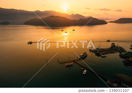 Beautiful aerial view of luxury catamarans and local fishing boats anchored in a calm tropical bay during golden hour. Beautiful aerial view of luxury catamarans and local fishing boats anchored in a calm tropical bay during golden hour. 139031107
