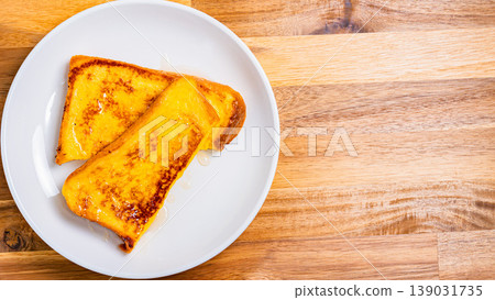 A close-up of honey-covered French toast, presented on a white plate, resembling a breakfast image. 139031735