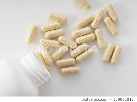 草藥補充劑膠囊從白色瓶子中傾瀉而出的圖片;保健食品或傳統中藥的圖片(正上方)。 草藥補充劑膠囊從白色瓶子中傾瀉而出的圖片;保健食品或傳統中藥的圖片(正上方)。 139031812