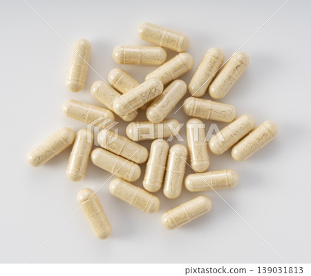 A bird's-eye view of herbal supplement capsules gathered against a white background. 139031813