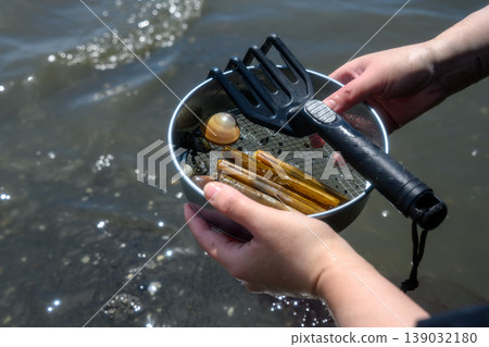 A woman's hands as she collects razor clams during clam digging. A woman's hands as she collects razor clams during clam digging. 139032180
