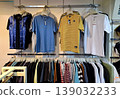 Yogyakarta, Indonesia - March 18th 2026: Rows of colorful T-shirts, a blue denim jacket, and various casual garments neatly arranged on metal hangers in a modern clothing store. 139032233