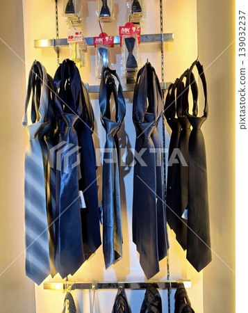 Yogyakarta, Indonesia - March 18th 2026: Collection of stylish neckties in shades of blue, grey, and black, neatly displayed on a store rack under warm lighting Yogyakarta, Indonesia - March 18th 2026: Collection of stylish neckties in shades of blue, grey, and black, neatly displayed on a store rack under warm lighting 139032237
