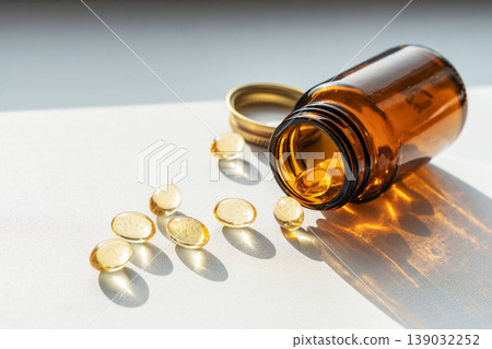 Glass dark bottle spilling vitamin pills, symbolizing daily health and wellness supplements, enhancing personal healthcare. Pills spilling from bottle for health treatments Glass dark bottle spilling vitamin pills, symbolizing daily health and wellness supplements, enhancing personal healthcare. Pills spilling from bottle for health treatments 139032252