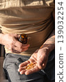 Mans hands holding a handful of fish oil capsules poured from a brown bottle, promoting daily health and wellness. Healthy lifestyle, self-care 139032254