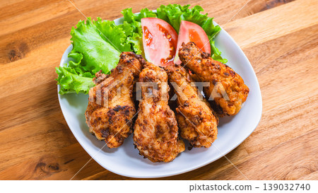 Deep-fried chicken wings with lettuce and tomato as a side dish, served on a white plate – a home-style meal. Deep-fried chicken wings with lettuce and tomato as a side dish, served on a white plate – a home-style meal. 139032740