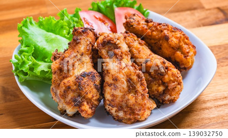Deep-fried chicken wings with lettuce and tomato as a side dish, served on a white plate – a home-style meal. Deep-fried chicken wings with lettuce and tomato as a side dish, served on a white plate – a home-style meal. 139032750