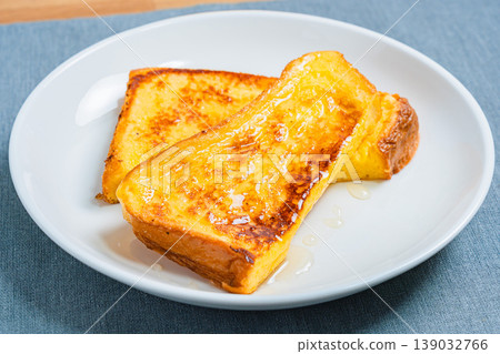 A close-up of honey-covered French toast, presented on a white plate, resembling a breakfast image. 139032766