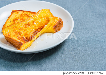 A close-up of honey-covered French toast, presented on a white plate, resembling a breakfast image. 139032767