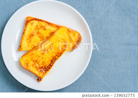 A close-up of honey-covered French toast, presented on a white plate, resembling a breakfast image. 139032773