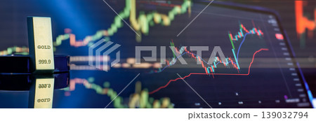 Online gold trading banner. Pure gold bullion bar and digital screen displaying financial market candlestick charts. 139032794