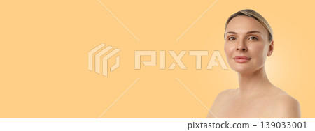 A woman confidently poses with a calm expression in soft lighting A woman confidently poses with a calm expression in soft lighting 139033001