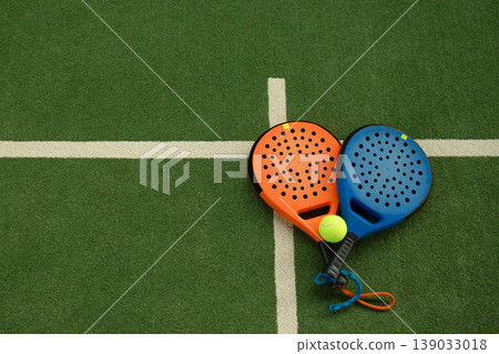 Padel rackets and a ball are placed on the court for play Padel rackets and a ball are placed on the court for play 139033018