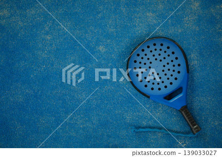 Padel racket rests on blue surface in sunny setting Padel racket rests on blue surface in sunny setting 139033027