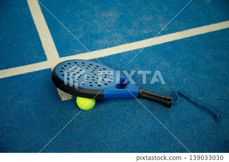 Padel rackets and balls are on blue padel court surface Padel rackets and balls are on blue padel court surface 139033030