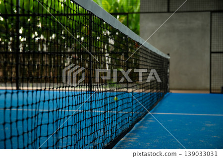 Padel court shows net and blue court in tropical area Padel court shows net and blue court in tropical area 139033031