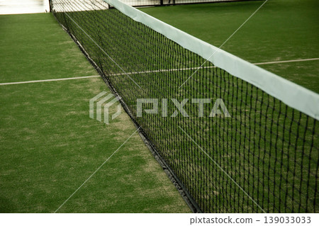Padel court features net and green turf for summer play Padel court features net and green turf for summer play 139033033
