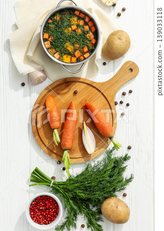 Carrots, potatoes, and a bowl of soup sit on a table Carrots, potatoes, and a bowl of soup sit on a table 139033118