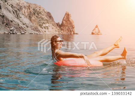 Woman floating sea, joyful young female relaxing on inflatable ring near scenic coastal cliffs during a summer vacation day Woman floating sea, joyful young female relaxing on inflatable ring near scenic coastal cliffs during a summer vacation day 139033142