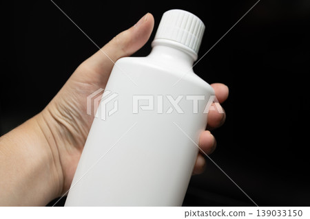 一隻男人的手拿著一瓶漱口水 一隻男人的手拿著一瓶漱口水 139033150