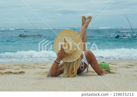 Woman on beach sand with a hat and coconut Woman on beach sand with a hat and coconut 139033213