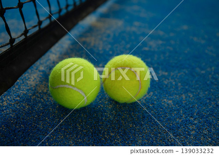 Padel balls sit on bright blue court surface by net 139033232