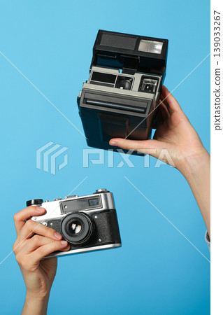 Two hands hold a vintage camera and an instant camera Two hands hold a vintage camera and an instant camera 139033267