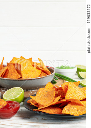 Tortilla chips are placed on two plates with dips and lime 139033272