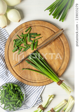 Chopped green onions on a wooden board with whole onions nearby Chopped green onions on a wooden board with whole onions nearby 139033279