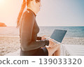 Woman Laptop Beach Working Remotely on Sandy Shore at Sunset 139033320