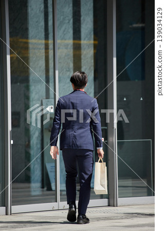 A male businessman walking through the bustling downtown area of Nagoya during the daytime. 139034129