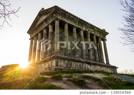 Ancient Garni temple bathed in golden sunset light, surrounded by bare trees and grass Ancient Garni temple bathed in golden sunset light, surrounded by bare trees and grass 139034360