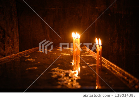 Lit candles in dark church interior, prayer and spirituality concept 139034393