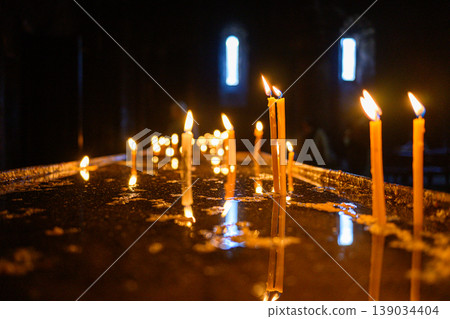 Lit candles in dark church interior, prayer and spirituality concept Lit candles in dark church interior, prayer and spirituality concept 139034404