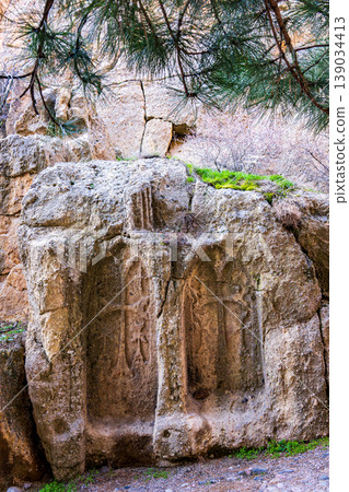 Weathered stone carvings embedded in a rocky cliff 139034413