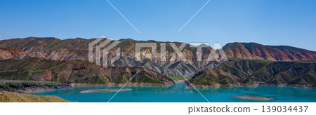Landscape with bright blue lake surrounded by layered mountain slopes Landscape with bright blue lake surrounded by layered mountain slopes 139034437