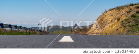View from road leading toward hilly terrain 139034490