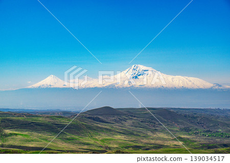 Panoramic view of majestic snow-covered Ararat peaks against bright blue sky Panoramic view of majestic snow-covered Ararat peaks against bright blue sky 139034517