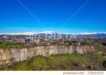 Urban sprawl at edge of cliff with distant snowy peaks Urban sprawl at edge of cliff with distant snowy peaks 139034559