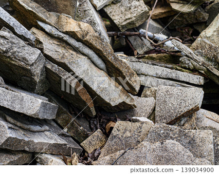 Layered stone chunks stacked unevenly in a heap. Macro shot of fragile geological texture, featuring brittle mineral edges and a precarious balance of sediment debris in a chaotic structure. 139034900