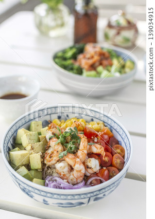 shrimp with avocado and mixed vegetables poke salad bowl on white table in outdoor cafe 139034915
