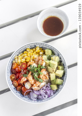 shrimp with avocado and mixed vegetables poke salad bowl on white table in outdoor cafe shrimp with avocado and mixed vegetables poke salad bowl on white table in outdoor cafe 139034919