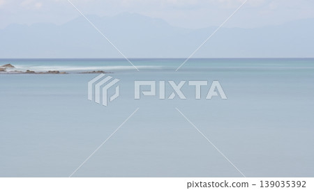 A calm sea in early summer, with a blue gradient background captured using a slow shutter speed. 139035392